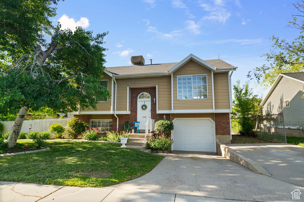 Split foyer home featuring brick siding, driveway, and an attached garage