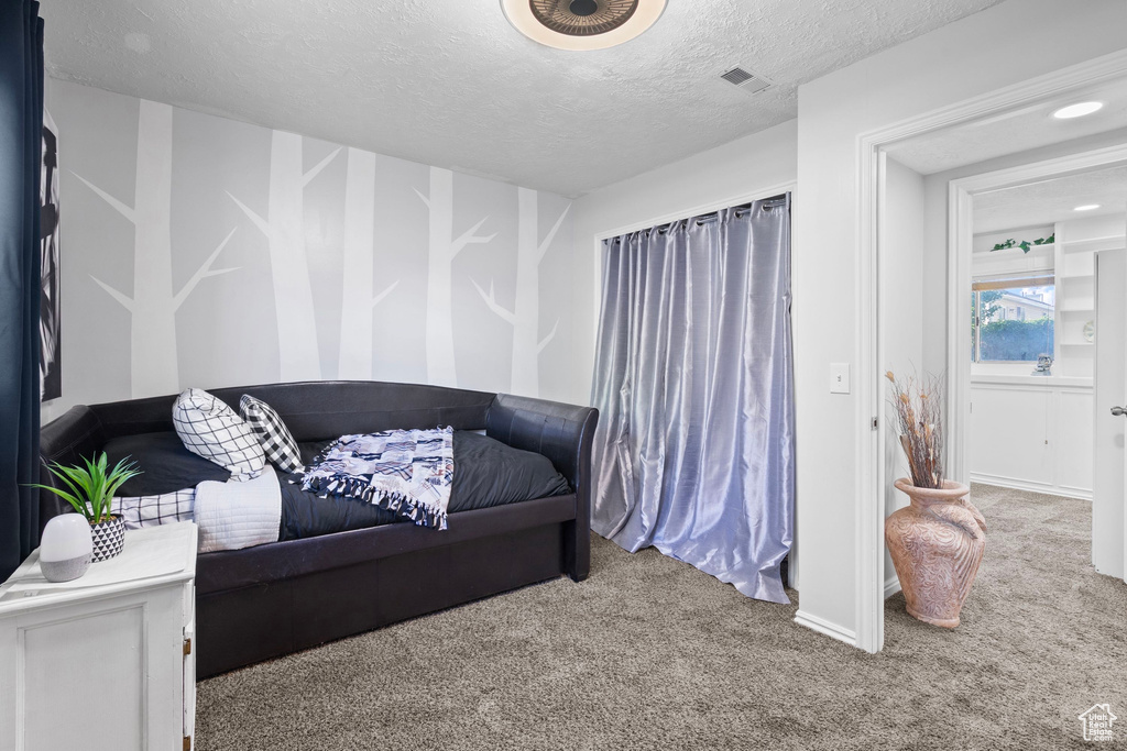 Living room with carpet floors, a textured ceiling, and baseboards