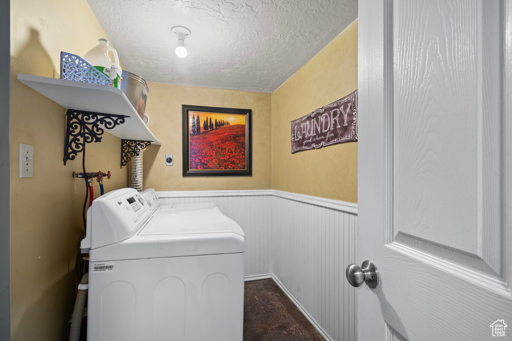Laundry area with washing machine and dryer, wainscoting, and a textured ceiling