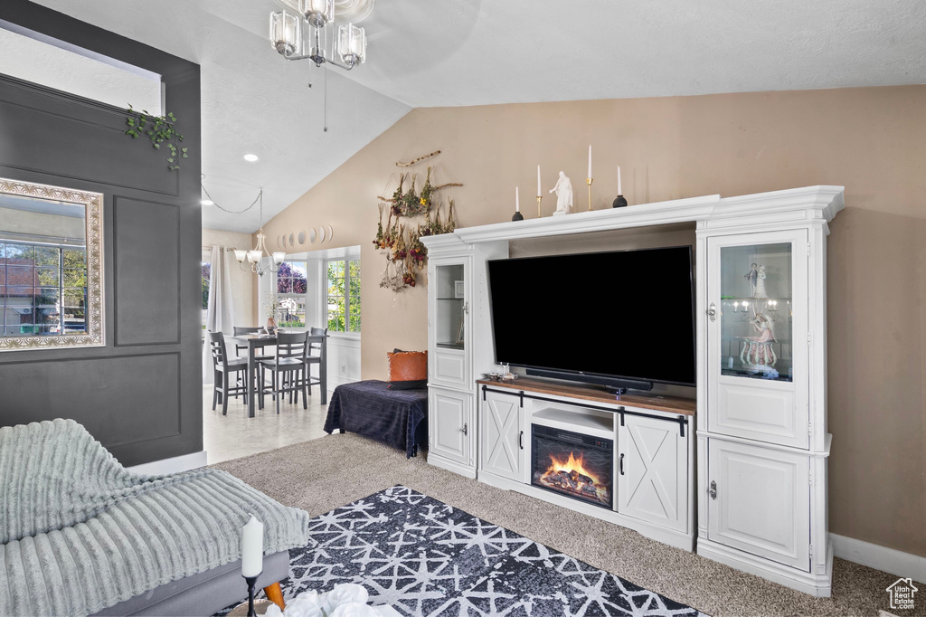 Living room with lofted ceiling, ceiling fan, a chandelier, and baseboards