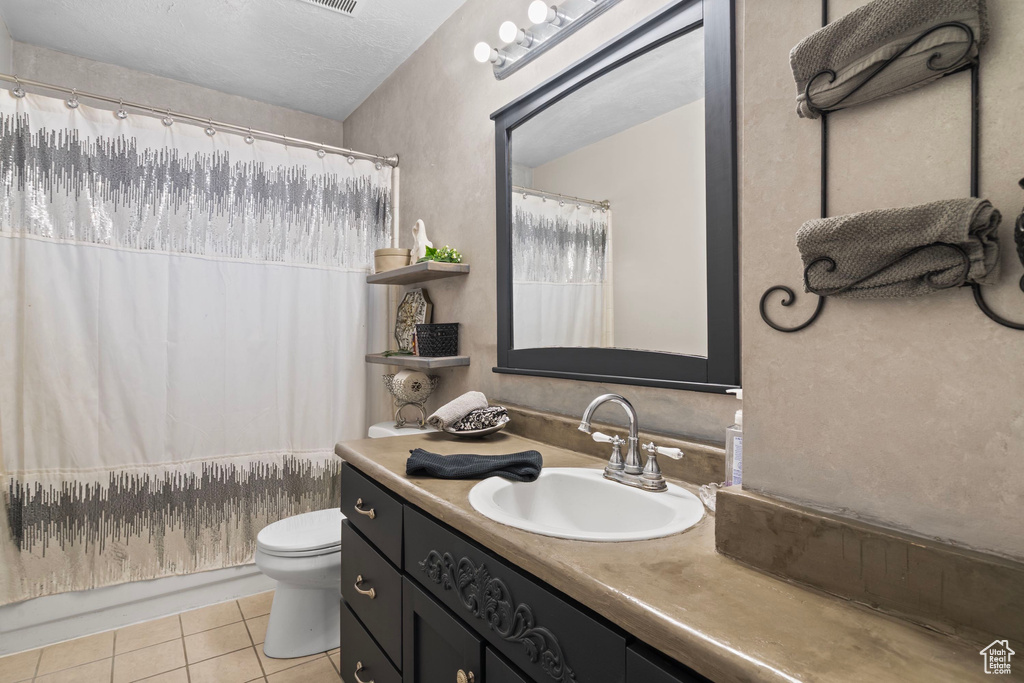 Bathroom with tile patterned flooring, toilet, vanity, and shower / tub combo with curtain