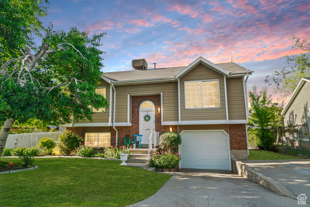 Split foyer home with brick siding, a garage, and concrete driveway