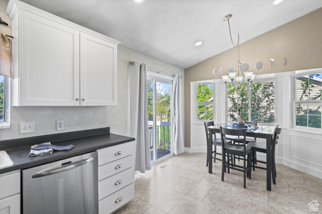Kitchen featuring stainless steel dishwasher, vaulted ceiling, dark countertops, a chandelier, and white cabinets