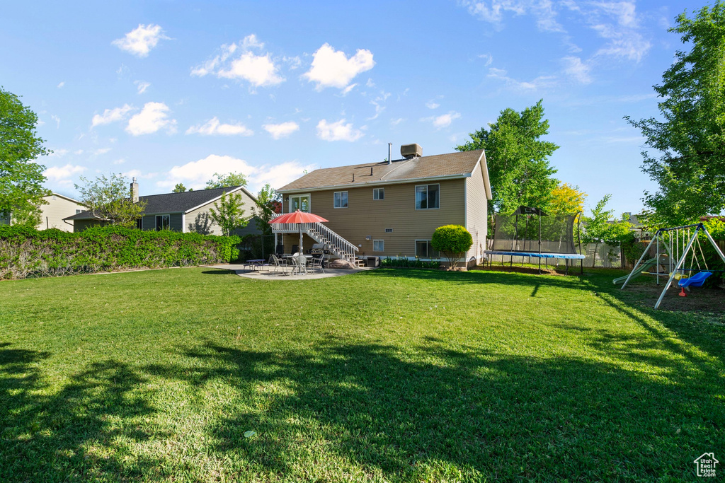 Back of property featuring a trampoline, a patio, and a playground