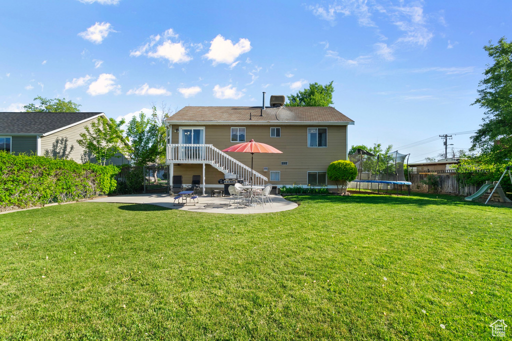 Back of property featuring a trampoline and a patio area