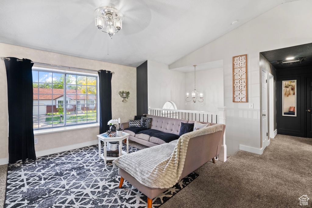 Carpeted living room featuring lofted ceiling, baseboards, ceiling fan, and a chandelier
