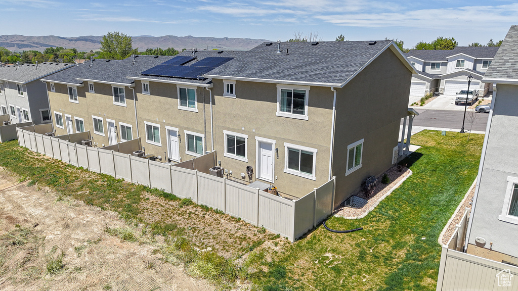 Rear view of property featuring stucco siding, a residential view, fence, and a mountain view
