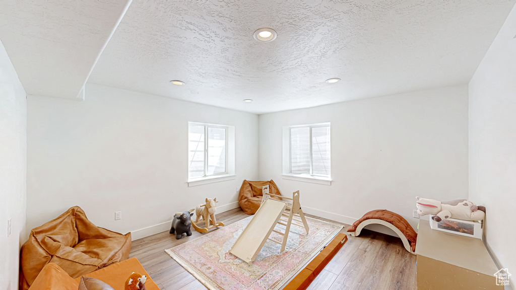 Playroom with a textured ceiling, recessed lighting, baseboards, and light wood-type flooring
