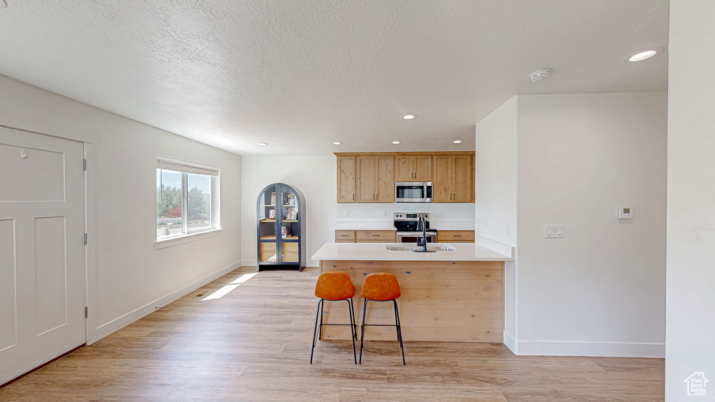 Kitchen featuring stainless steel appliances, light wood-style floors, baseboards, recessed lighting, and a textured ceiling