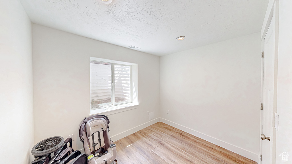 Unfurnished office with light wood-style flooring, baseboards, a textured ceiling, and recessed lighting