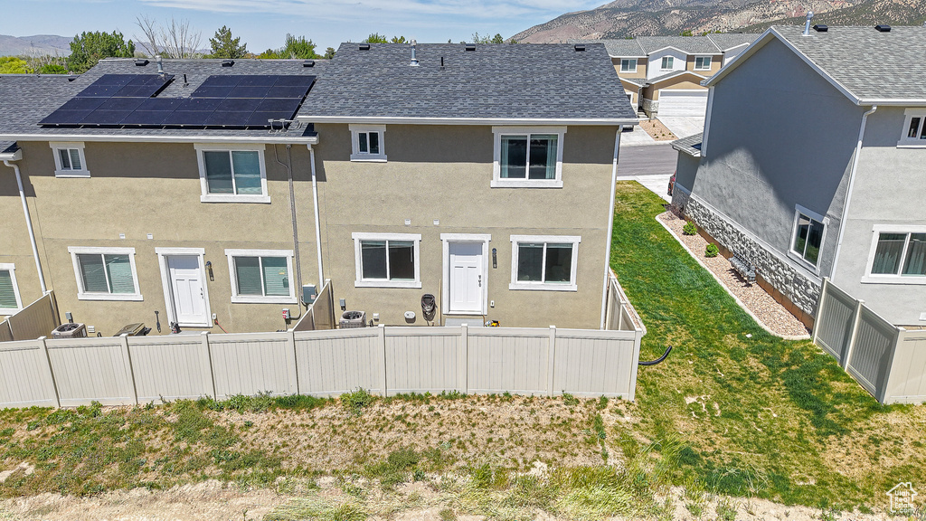 Back of property with a mountain view, stucco siding, a shingled roof, and fence