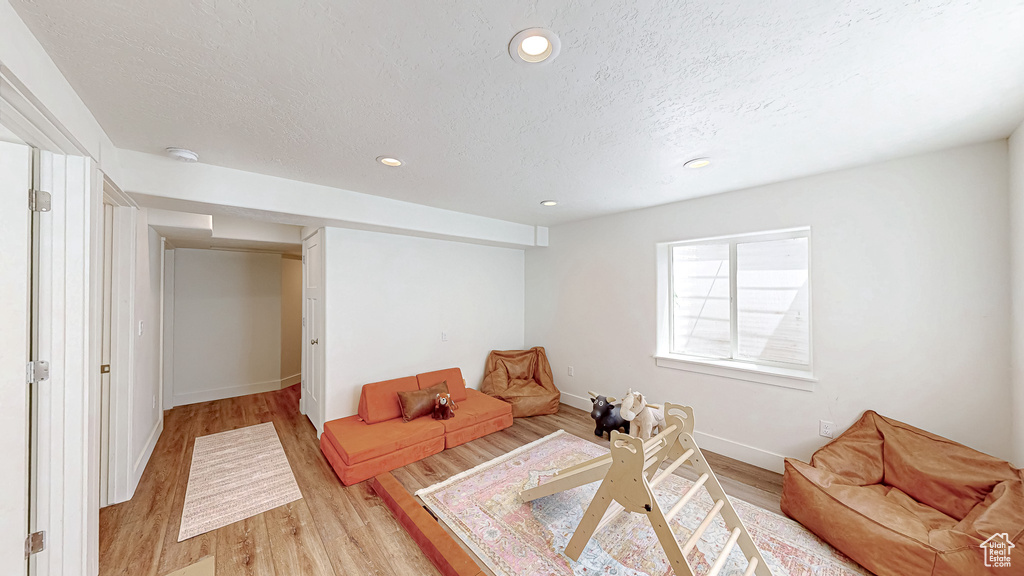 Living area with light wood-type flooring, baseboards, a textured ceiling, and recessed lighting
