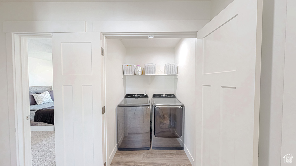 Laundry room featuring independent washer and dryer, baseboards, and light wood-type flooring