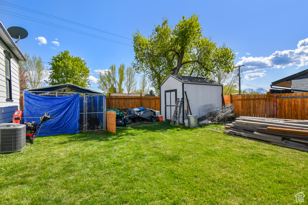 View of yard with central air condition unit, a storage unit, and an outbuilding