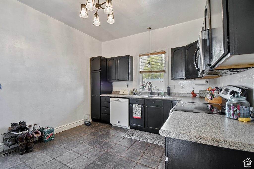 Kitchen featuring white dishwasher, electric stove, a sink, a chandelier, and hanging light fixtures