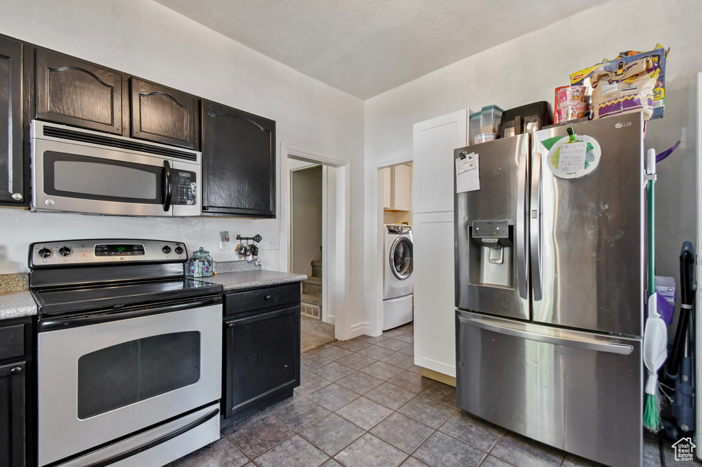 Kitchen with stainless steel appliances, washer / dryer, tile patterned floors, light countertops, and baseboards