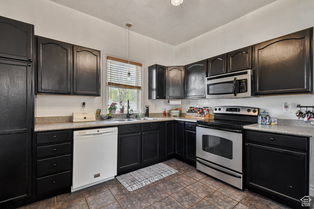 Kitchen with appliances with stainless steel finishes, a sink, pendant lighting, and light countertops