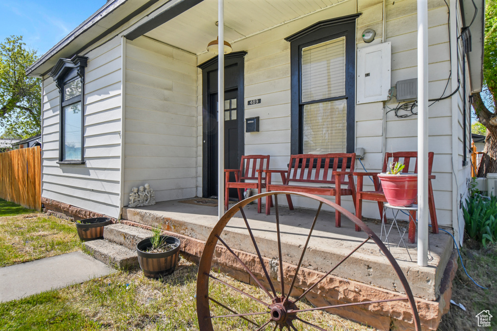 Property entrance featuring covered porch, electric panel, and fence
