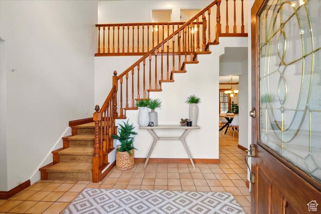 Entrance foyer featuring baseboards, stairway, light tile patterned flooring, and a chandelier