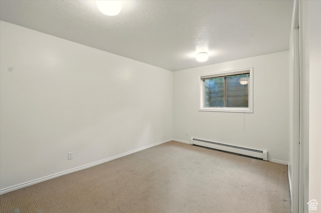 Spare room with a baseboard radiator, carpet, and baseboards