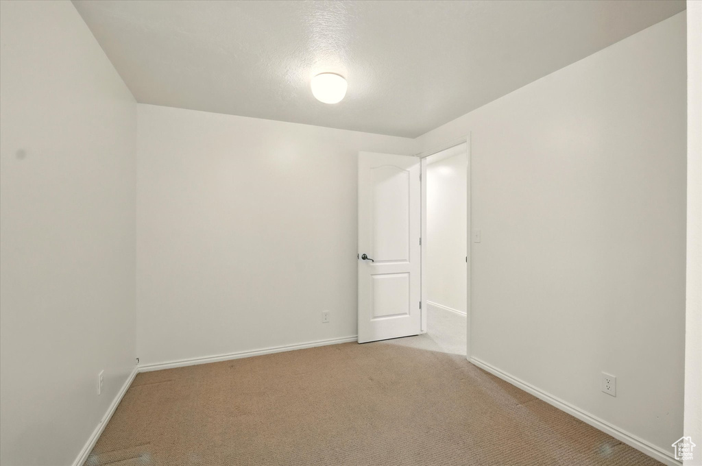 Empty room with light colored carpet and baseboards