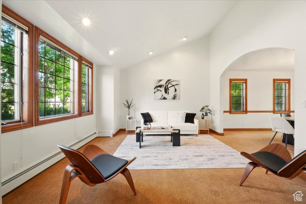 Living area featuring light carpet, arched walkways, healthy amount of natural light, lofted ceiling, and recessed lighting