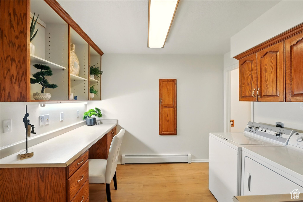 Laundry area featuring a baseboard radiator, cabinet space, washing machine and clothes dryer, light wood-type flooring, and an office area
