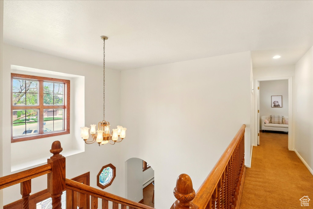 Hallway with an upstairs landing, a chandelier, light carpet, baseboards, and recessed lighting