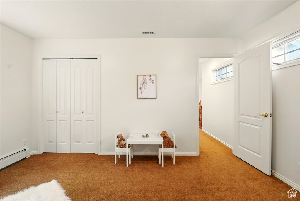 Bedroom with carpet flooring, a closet, baseboards, and baseboard heating