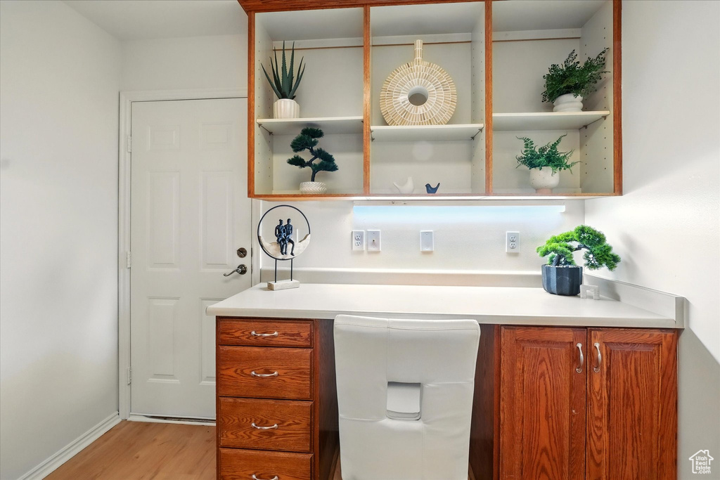 Bar with light wood-style flooring, built in desk, and baseboards