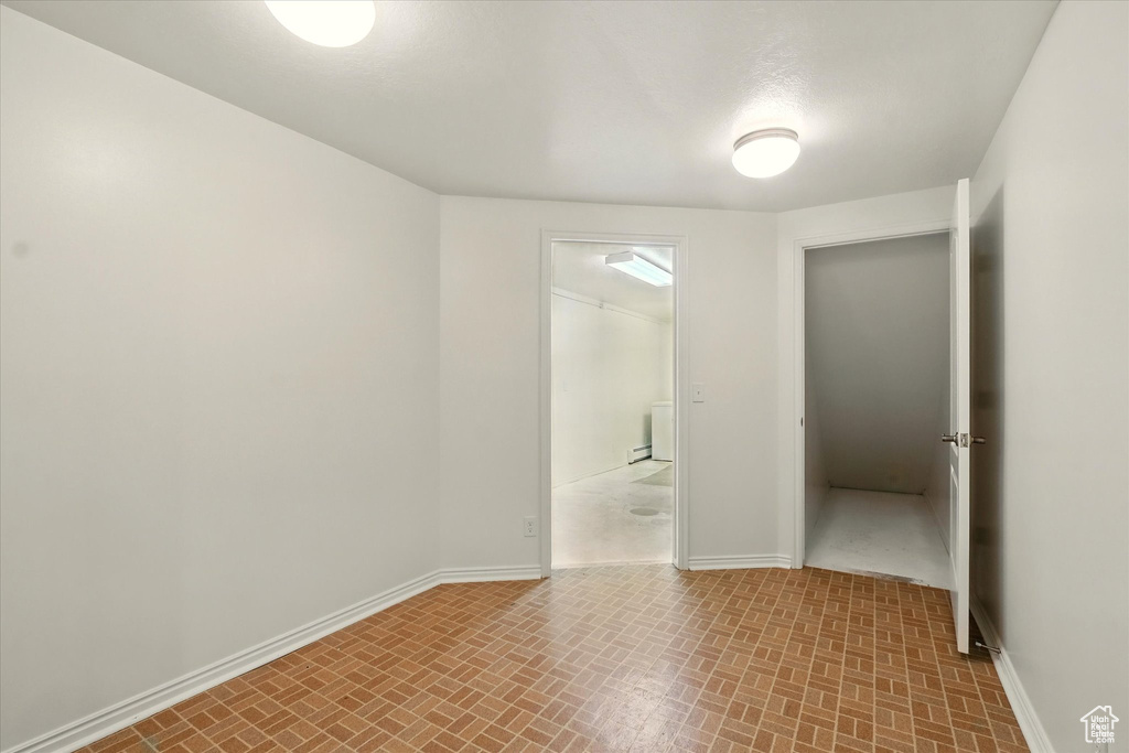 Unfurnished room with baseboards and brick patterned floors