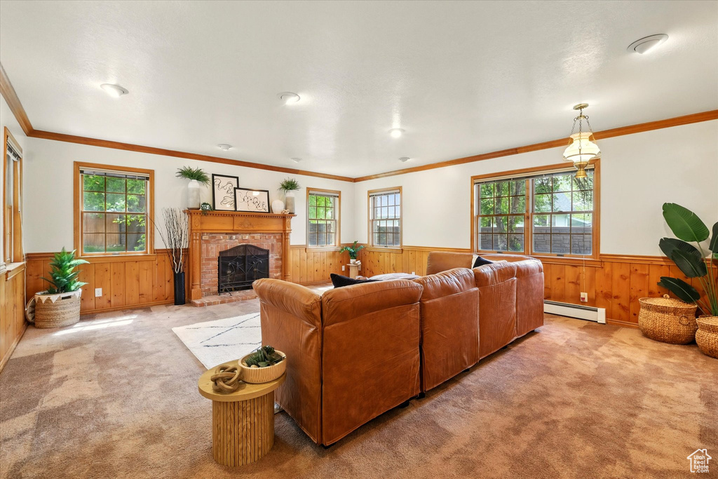 Living room with a baseboard radiator, a wainscoted wall, wood walls, carpet flooring, and a brick fireplace