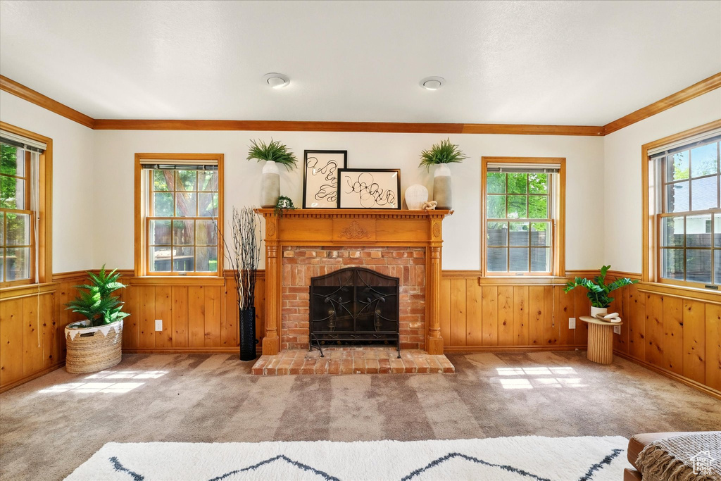 Living area featuring a wainscoted wall, healthy amount of natural light, a brick fireplace, wood walls, and ornamental molding