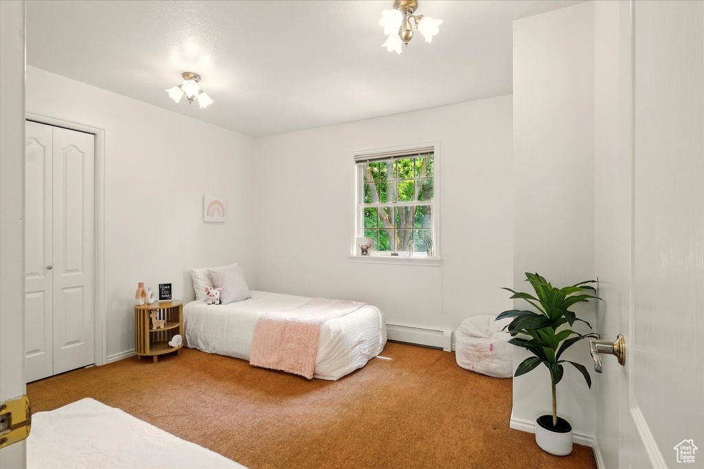 Bedroom with a baseboard radiator, carpet, a closet, and baseboards