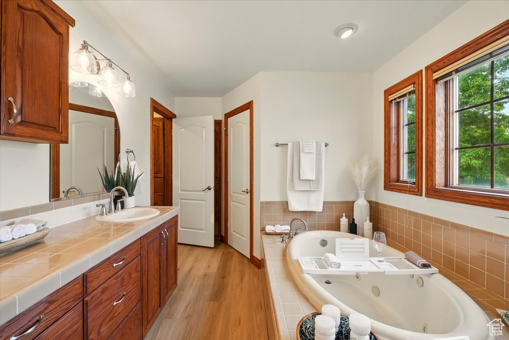 Bathroom with a tub with jets, wood finished floors, and vanity