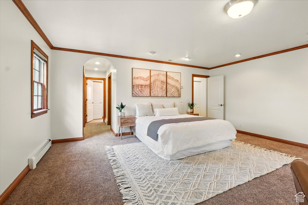 Bedroom featuring a baseboard heating unit, carpet floors, baseboards, arched walkways, and crown molding