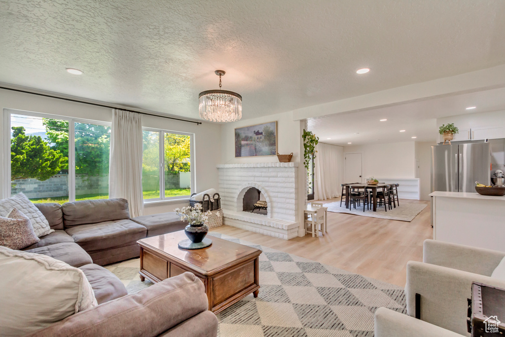 Living room featuring recessed lighting, light wood-style flooring, a chandelier, and a fireplace