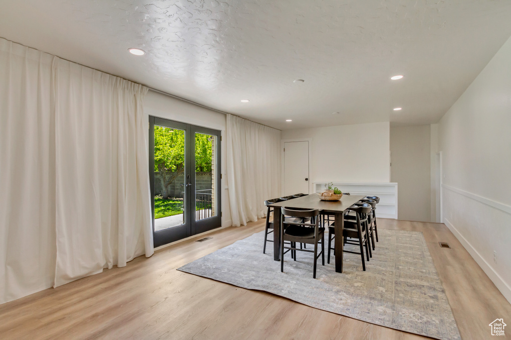 Dining space with french doors, light wood-style flooring, and recessed lighting