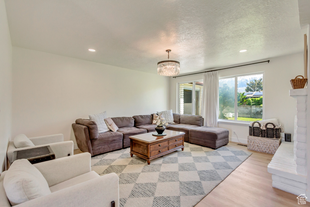 Living area with light wood-style flooring, recessed lighting, a chandelier, a textured ceiling, and baseboards