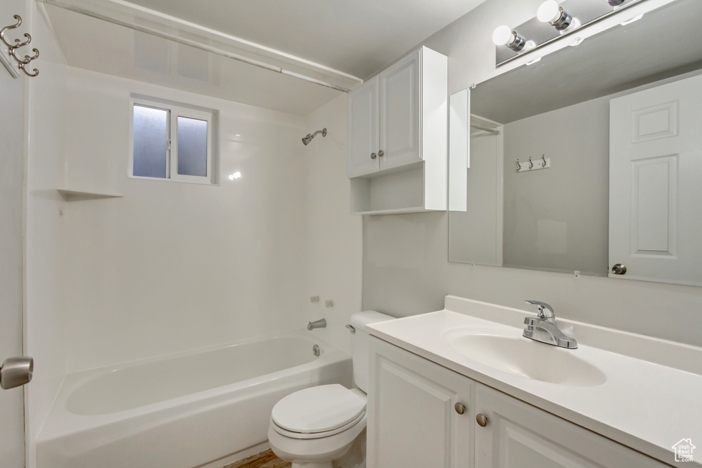 Bathroom featuring toilet,  shower combination, and vanity