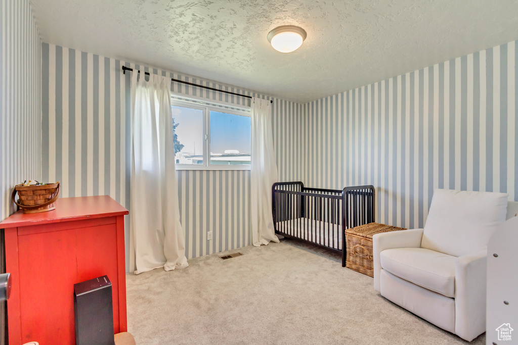 Carpeted bedroom featuring a textured ceiling and wallpapered walls