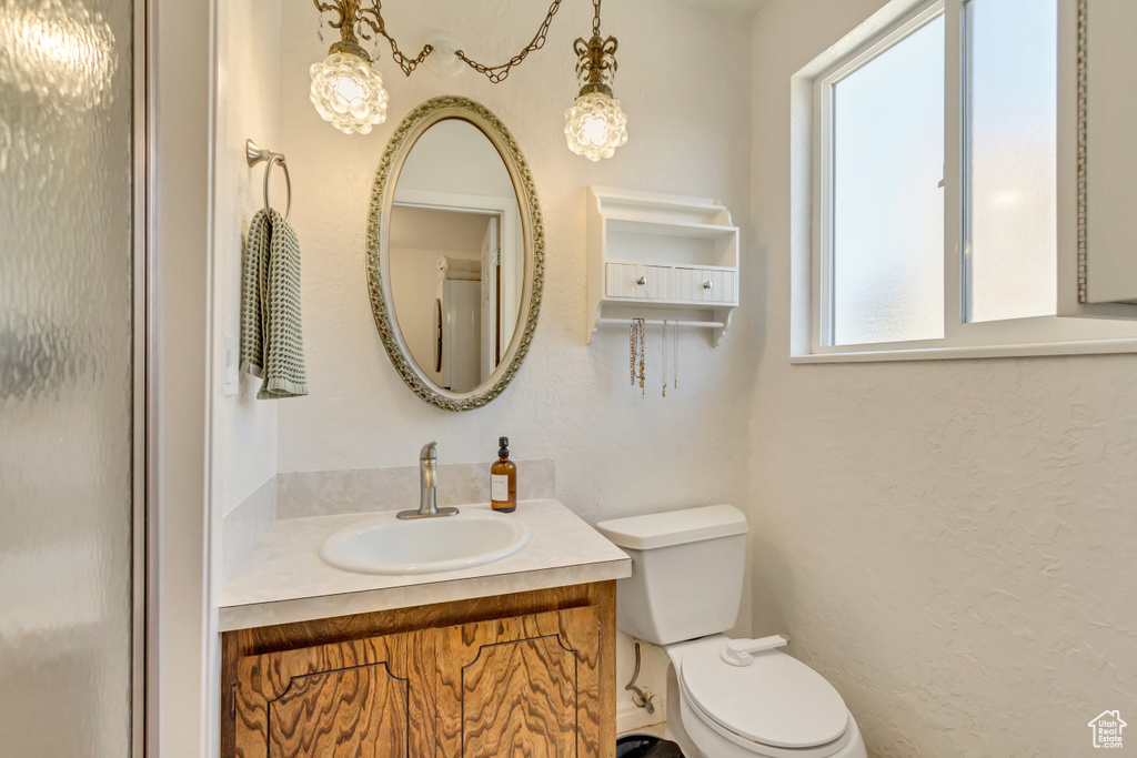 Bathroom with toilet, vanity, and a textured wall