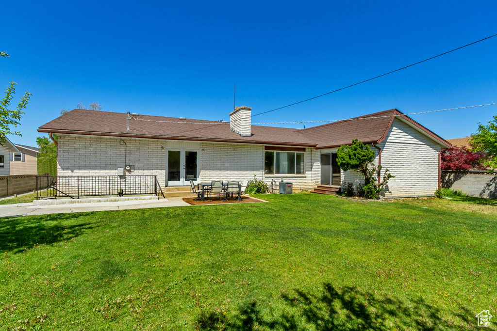Rear view of house featuring entry steps, a chimney, french doors, and central air condition unit