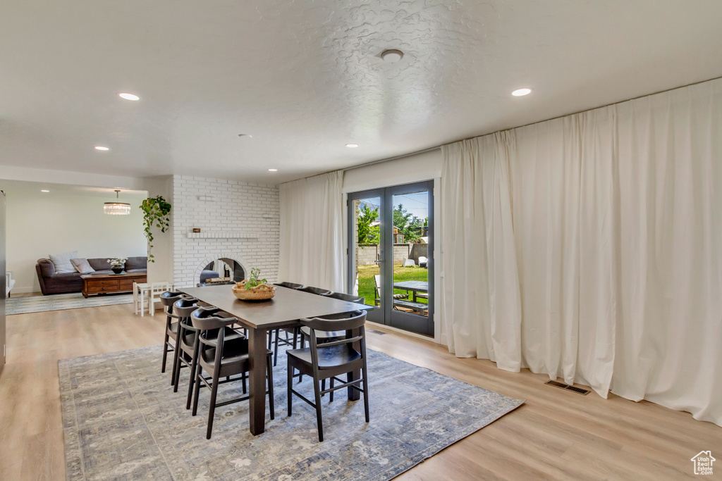 Dining area with a brick fireplace, light wood-style floors, and recessed lighting