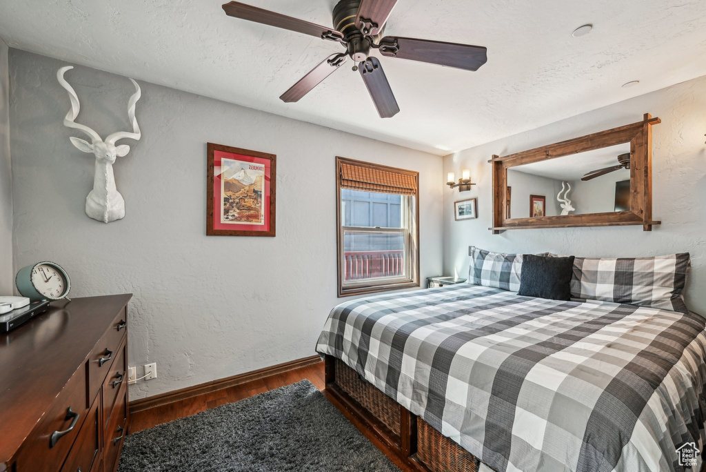 Bedroom featuring wood finished floors, baseboards, a ceiling fan, and a textured ceiling