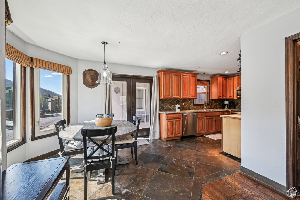 Kitchen with stainless steel dishwasher, backsplash, light countertops, decorative light fixtures, and recessed lighting