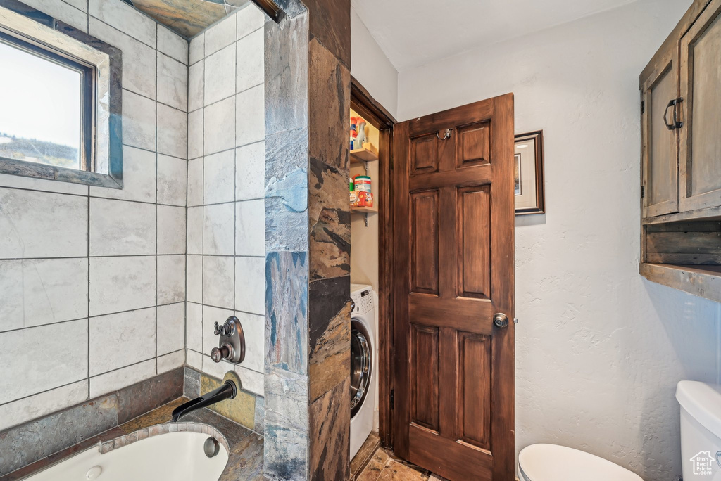 Full bathroom featuring toilet, washer / clothes dryer, and  shower combination