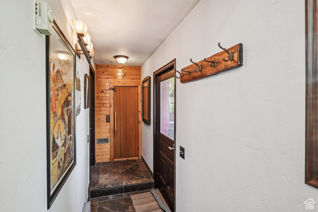 Hall with dark stone finish floors and wooden walls