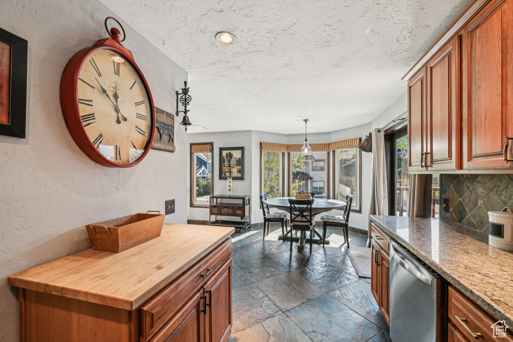 Kitchen with wooden counters, stone tile flooring, stainless steel dishwasher, tasteful backsplash, and brown cabinets