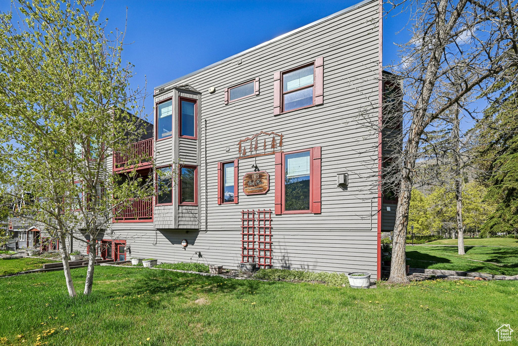 Back of house featuring a balcony and a lawn